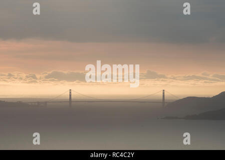 Il Golden Gate Bridge di San Francisco come si vede da lontano in Berkeley Hills durante un bel tramonto quando il cielo era di colore arancione. Foto Stock