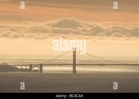 Il Golden Gate Bridge di San Francisco come si vede da lontano in Berkeley Hills durante un bel tramonto quando il cielo era di colore arancione. Foto Stock