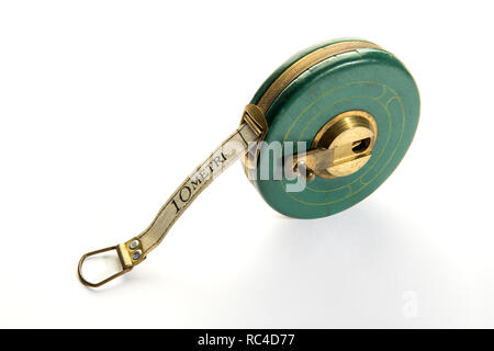 10 metro di misura vintage un nastro o una fettuccia-misurare nel verde rotondo con corpo in metallo giallo maniglia. Vista da un angolo alto in close-up, isolato su bianco Foto Stock