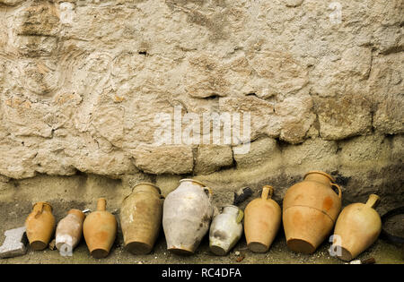 Due tradizionali grandi vasi di creta per acqua di storage abbandonati per strada. Pld muro di pietra dello sfondo. Foto Stock