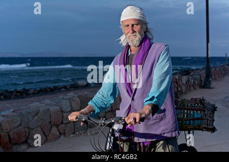 Invecchiamento hippie maschio su una bicicletta Foto Stock