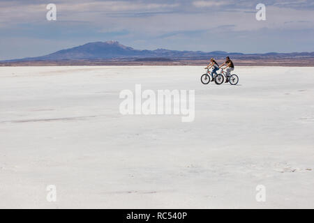 Una giovane coppia impostato su l'avventura di una vita come ciclo di essi attraverso il vasto e aprire il Salar de Uyuni godendo la libertà e le belle viste. Foto Stock