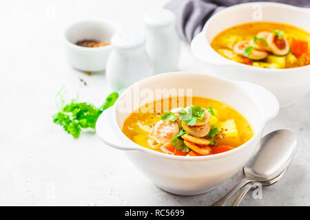 Il tedesco la zuppa di patate con salsicce e verdure in bianco bocce, sfondo bianco. La cucina tedesca ricette. Foto Stock