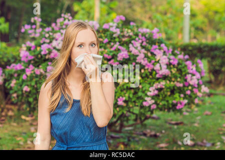 Allergia da polline concetto. Giovane donna sta per starnutire. Alberi fioriti in background Foto Stock
