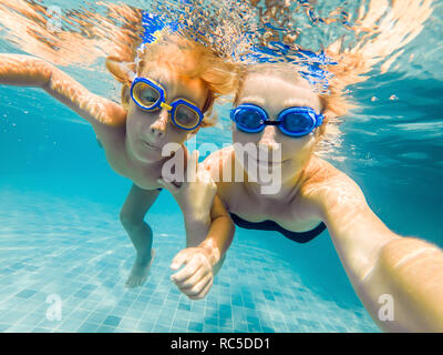 Madre e figlio in immersioni occhiali nuotare nella piscina sotto l'acqua