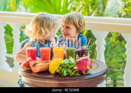 Bambini bere colorati Frullati salutari.. Anguria, papaia, mango, spinaci e dragon frutta. I frullati, succhi di frutta, bevande, bevande con varietà di frutta fresca su una tavola di legno Foto Stock