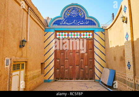 YAZD, Iran, 18 ottobre 2017: La scenic gate, decorata con piastrelle motivi e la massiccia porta di legno della storica gate, occupata da Yazd Bar associ Foto Stock