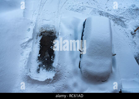 Una macchina parcheggiata sotto un sacco di neve e svuotare lo spazio di parcheggio Foto Stock