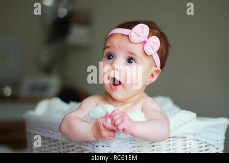 Carino Baby girl, con una prua su i suoi capelli, con lo stupore di fronte Foto Stock