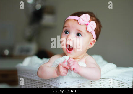 Carino Baby girl, con una prua su i suoi capelli, con lo stupore di fronte Foto Stock