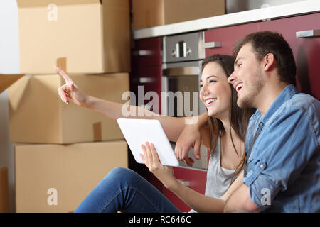 Coppia felice in movimento pianificazione home riforma tenendo un tablet in cucina Foto Stock