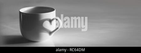 A forma di cuore ad ombra su una tazza di caffè, in bianco e nero Foto Stock
