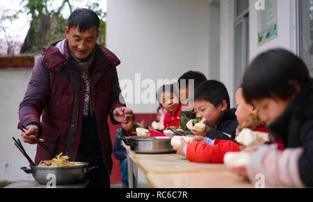 (190114) -- NANCHANG, 14 gennaio 2019 (Xinhua) -- PRESIDE Zhang Zhanliang distribuisce il pasto per gli studenti di Huangni scuola elementare di Chuntao città di Yujiang distretto della città Yingtan, Cina orientale della provincia di Jiangxi, Gen 3, 2019. Zhang Zhanliang, il principale di Huangni scuola primaria, è stato conosciuto a livello nazionale di recente per prendersi cura della scuola a sinistra dietro i bambini i cui genitori sono lavoratori migranti nei paesi e nelle città. Per anni, non c'è la mensa a Huangni scuola elementare. Designato come principale nel 2018, Zhang Zhanliang speso denaro proprio per la cottura pasto aggiuntivo per questi di sinistra Foto Stock