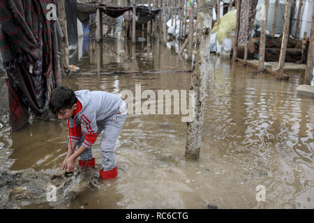 13 gennaio 2019, Libano, Barelias: UN RIFUGIATO siriano boy sorge in acqua nella parte anteriore della tenda allagata dopo Pesanti rovesci al Barelias Refugee Camp. Una cinque giorni di tempesta la settimana scorsa hanno devastato campi con migliaia di rifugiati siriani e ora sono loro stessi di controventamento per un altro grande tempesta nei prossimi giorni. Foto: Marwan Naamani/dpa Foto Stock