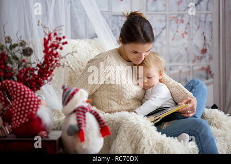 La madre di allattamento al seno il suo bambino figlio seduto in poltrona  accogliente, nevicava fuori stagione invernale Foto stock - Alamy