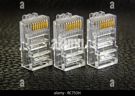 Tre connettori RJ-45 in una fila di close-up su sfondo scuro Foto Stock