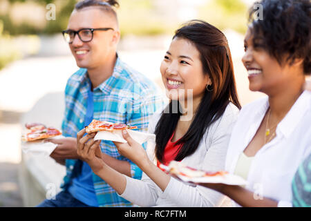 Happy amici mangiando panini e pizza all'aperto Foto Stock