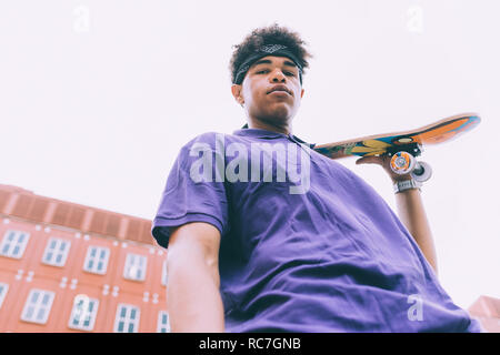 Guidatore di skateboard in posa con lo skateboard, Milano, Italia Foto Stock