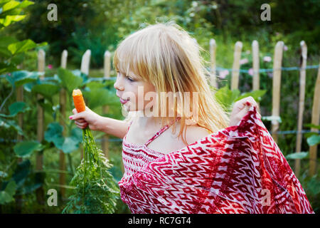 Ragazza di mangiare la carota nel campo Foto Stock