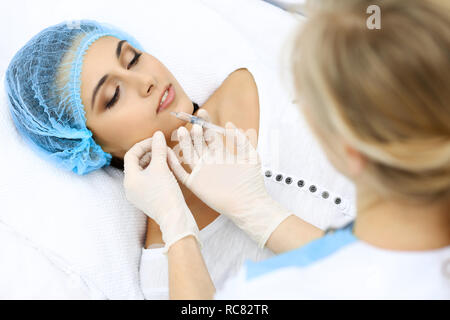 Professional cosmetologo rendendo iniezione in viso, labbra. Giovane donna ottiene la siringa con la carica per affrontare la contornazione o l'aumento. Invecchiamento facciale, ringiovanimento e procedure di idratazione Foto Stock