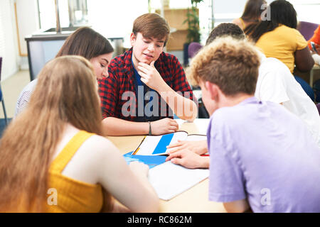 Maschi e femmine di istruzione superiore gli studenti a discutere di progetto in college classroom Foto Stock