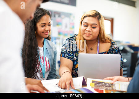 Maschi e femmine di istruzione superiore agli studenti di lavorare in team e utilizzando laptop in college classroom Foto Stock