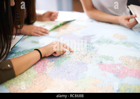 Gli studenti universitari che studiano la mappa del mondo in classe Foto Stock