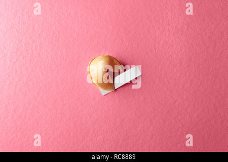 Fortune cookie con carta bianca su sfondo rosa Foto Stock