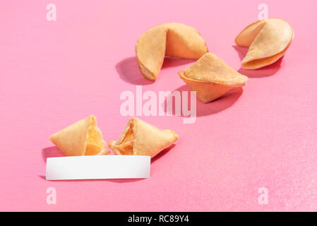 Rotture di fortune cookie con carta bianca su sfondo rosa Foto Stock