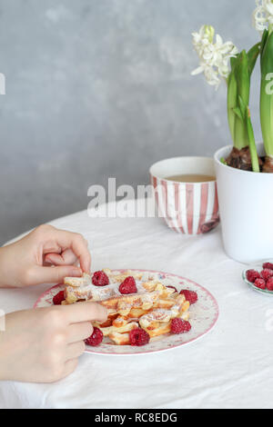 Tavolo per la colazione con waffles freschi e lamponi e tè sul tavolo Foto Stock