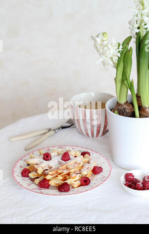 Tavolo per la colazione con waffles freschi e lamponi sul tavolo Foto Stock