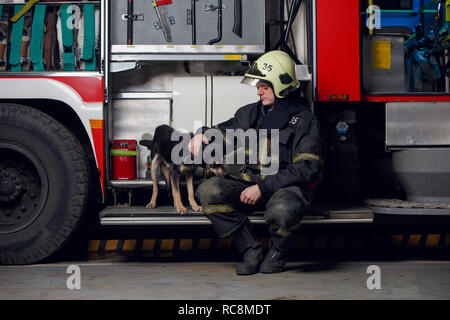 Immagine del vigile del fuoco nel casco con il cane Foto Stock