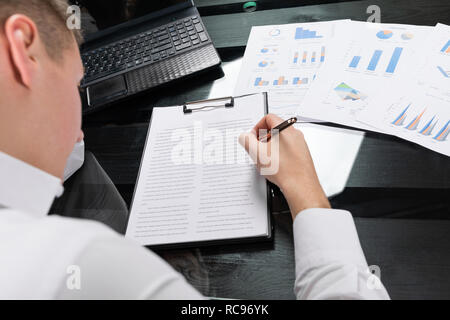 Giovane uomo segni assicurazione in ufficio luminoso Foto Stock