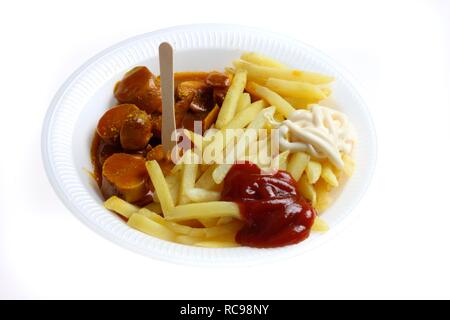 Il fast food, patatine fritte e salsiccia con il curry in polvere su di un piatto di carta con ketchup e maionese Foto Stock