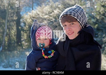 Mutter mit Baby im braccio, draußen inverno | madre che porta il suo bambino in braccio, al di fuori di inverno Foto Stock