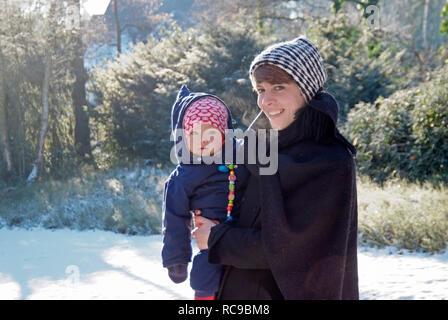 Mutter mit Baby im braccio, draußen inverno | madre che porta il suo bambino in braccio, al di fuori di inverno Foto Stock