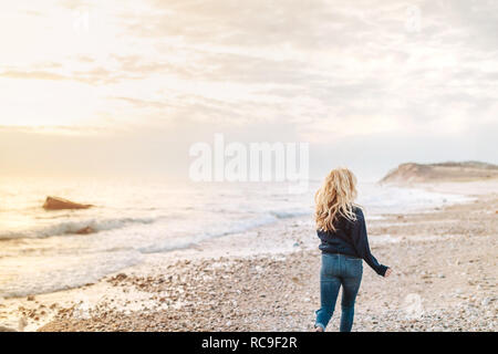 Giovane donna passeggiando lungo la spiaggia, vista posteriore, Menemsha, Martha's Vineyard, Massachusetts, STATI UNITI D'AMERICA Foto Stock