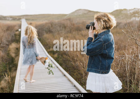 Giovane donna fotografare amico sulla duna costiera boardwalk, Menemsha, Martha's Vineyard, Massachusetts, STATI UNITI D'AMERICA Foto Stock