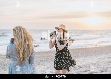 Giovane donna fotografare amico su windy beach, Menemsha, Martha's Vineyard, Massachusetts, STATI UNITI D'AMERICA Foto Stock