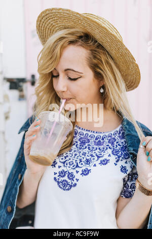 Giovane donna indossa alle imbarcazioni di bere caffè ghiacciato da paglia, Menemsha, Martha's Vineyard, Massachusetts, STATI UNITI D'AMERICA Foto Stock