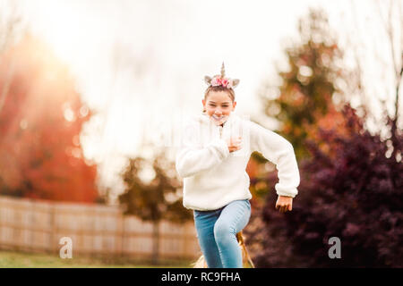 Ragazza con unicorn cerchietto per capelli in esecuzione in posizione di parcheggio Foto Stock