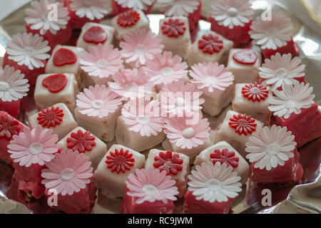 Colorato petit fours con decorazioni di fiori Foto Stock