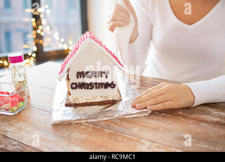 Donna che fa gingerbread house per natale Foto Stock