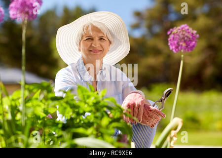 Donna senior con giardino potatore e fiori Foto Stock