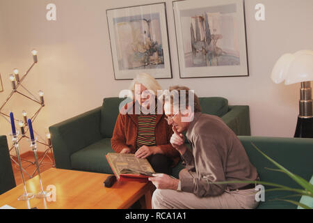 Pärchen mittleren altera schaut sich Fotoalbum un | middleaged giovane è alla ricerca di album di foto Foto Stock