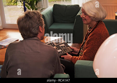 Pärchen mittleren altera schaut sich Fotoalbum un | middleaged giovane è alla ricerca di album di foto Foto Stock