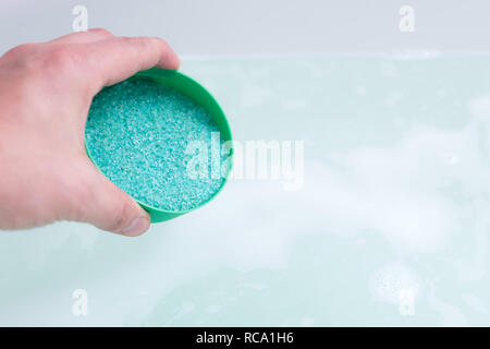 In prossimità dell'umana la mano bagno analizzato i cristalli di sale in acqua. Il trattamento termale, relax Foto Stock