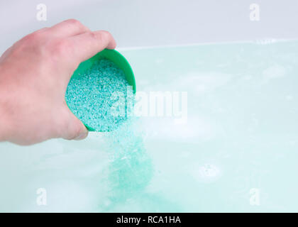 In prossimità dell'umana la mano bagno analizzato i cristalli di sale in acqua. Il trattamento termale, relax Foto Stock