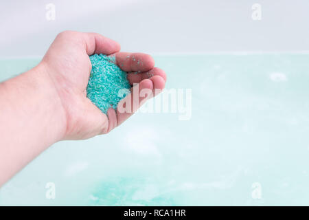 In prossimità dell'umana la mano bagno analizzato i cristalli di sale in acqua. Il trattamento termale, relax Foto Stock
