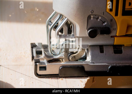 Joiner funziona sulla macchina con il prodotto di legno fabbricazione. Il falegname taglia il legno di varie configurazioni sulla macchina utensile.segagione di un bordo con una sagoma macchina. Foto Stock